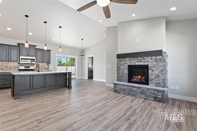 kitchen featuring open floor plan, light countertops, ceiling fan, light wood-style floors, and stainless steel appliances