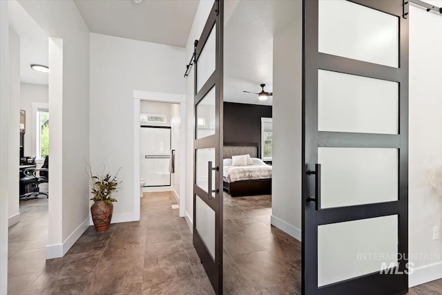 hallway with a barn door, an office area, and baseboards