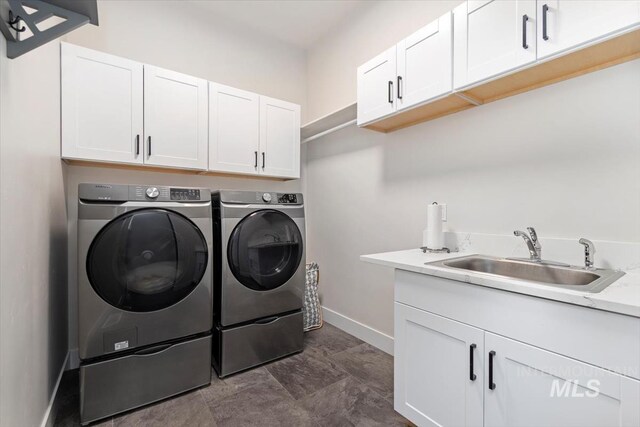 washroom featuring washer and clothes dryer, cabinet space, and baseboards