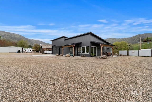 rear view of property featuring a mountain view and fence