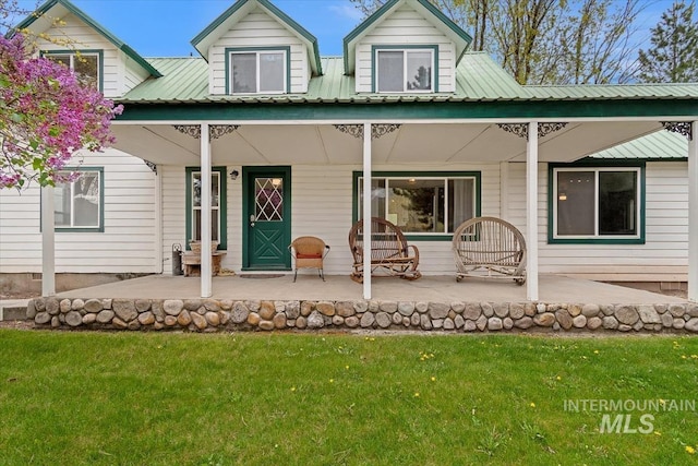 back of property with covered porch, a yard, and metal roof