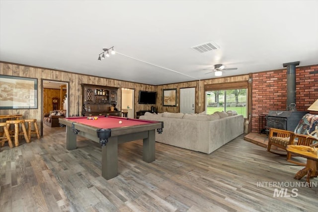 recreation room featuring a wood stove, billiards table, wood walls, a ceiling fan, and wood finished floors