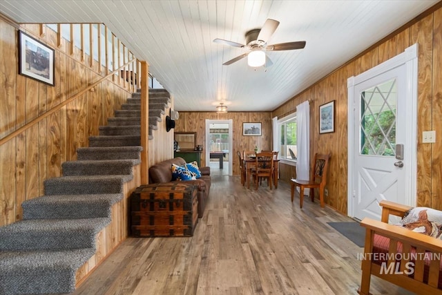entrance foyer featuring stairs, wood finished floors, a ceiling fan, and wood walls