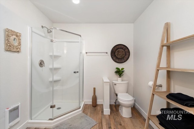 full bath featuring wood finished floors, a stall shower, toilet, and baseboards