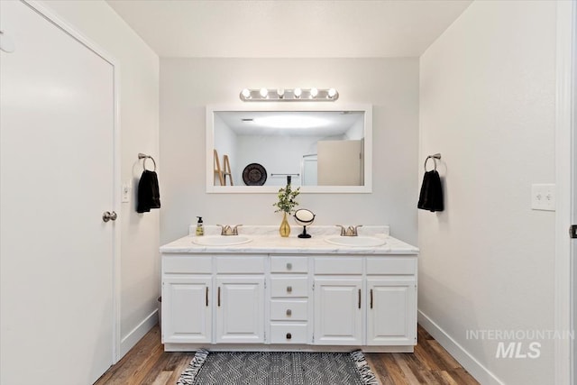 full bathroom with wood finished floors, double vanity, and baseboards