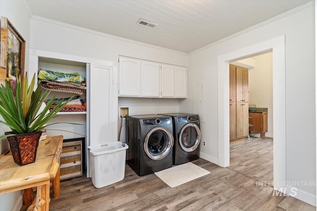 laundry area featuring crown molding, light wood finished floors, cabinet space, washing machine and dryer, and baseboards