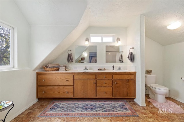 full bathroom featuring vaulted ceiling, a textured ceiling, double vanity, toilet, and baseboards