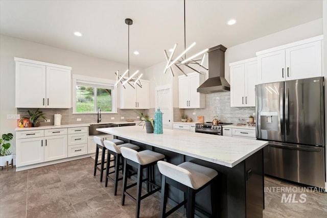 kitchen with appliances with stainless steel finishes, wall chimney exhaust hood, a center island, tasteful backsplash, and recessed lighting