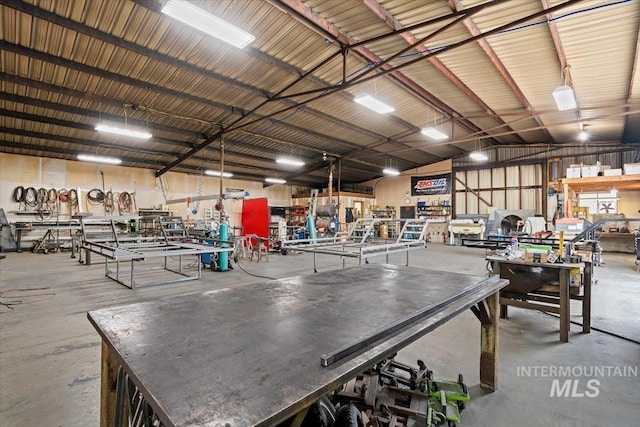 miscellaneous room with a workshop area, vaulted ceiling, concrete flooring, and metal wall