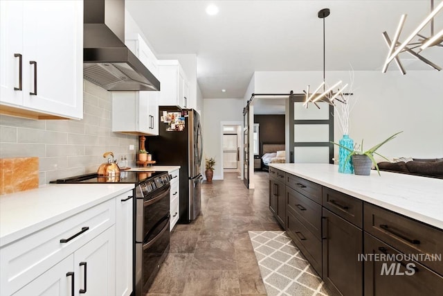 kitchen featuring wall chimney range hood, appliances with stainless steel finishes, open floor plan, and white cabinetry