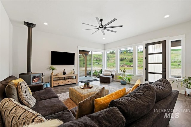 living area with ceiling fan, a wood stove, and recessed lighting