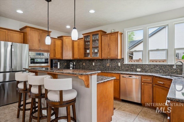4824 S Longmoor Ave, Boise, ID 83709 - kitchen featuring brown cabinets, appliances with stainless steel finishes, decorative backsplash, and a sink