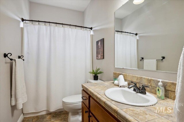 4824 S Longmoor Ave, Boise, ID 83709 - full bathroom with a shower with shower curtain, vanity, backsplash, and toilet
