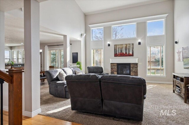 4824 S Longmoor Ave, Boise, ID 83709 - living area with light wood-style floors, a towering ceiling, a stone fireplace, and baseboards