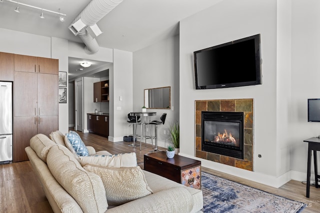 living room with a tile fireplace, wood finished floors, and baseboards