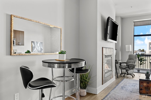 dining area featuring baseboards, a tiled fireplace, and wood finished floors