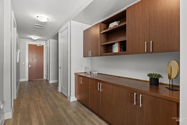 hallway with visible vents, baseboards, and wood finished floors