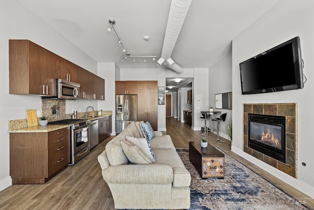 living area with baseboards, wood finished floors, and a tile fireplace