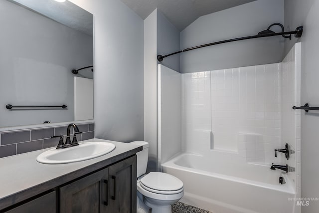 bathroom featuring toilet, vanity, tasteful backsplash, shower / bathtub combination, and vaulted ceiling