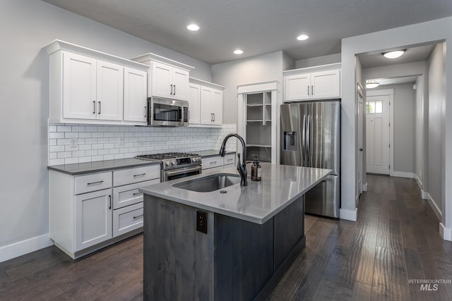 kitchen featuring appliances with stainless steel finishes, a sink, baseboards, dark wood-style floors, and tasteful backsplash