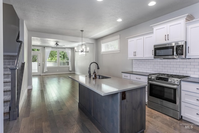 kitchen featuring stainless steel appliances, a sink, open floor plan, decorative backsplash, and white cabinetry