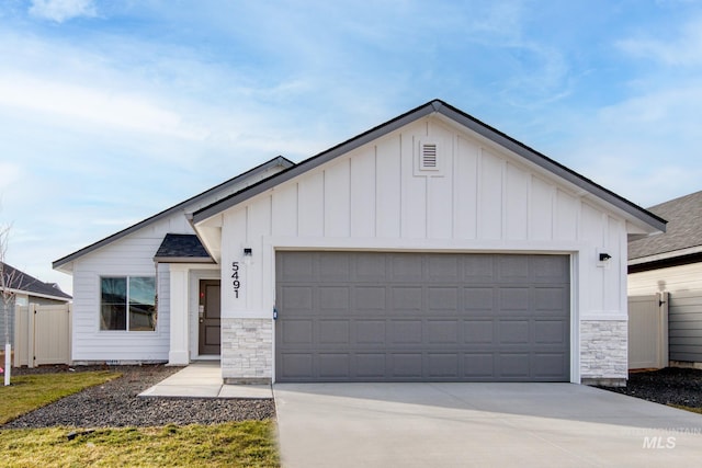 modern farmhouse style home featuring driveway, stone siding, and board and batten siding