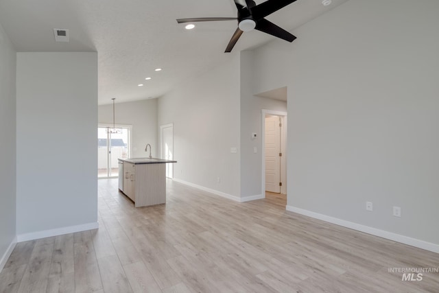 unfurnished living room featuring a sink, high vaulted ceiling, visible vents, light wood finished floors, and a ceiling fan