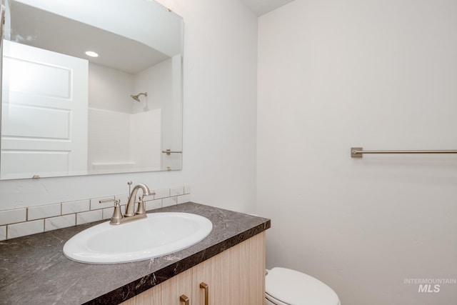 bathroom with walk in shower, vanity, and toilet