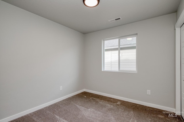 carpeted spare room featuring baseboards and visible vents
