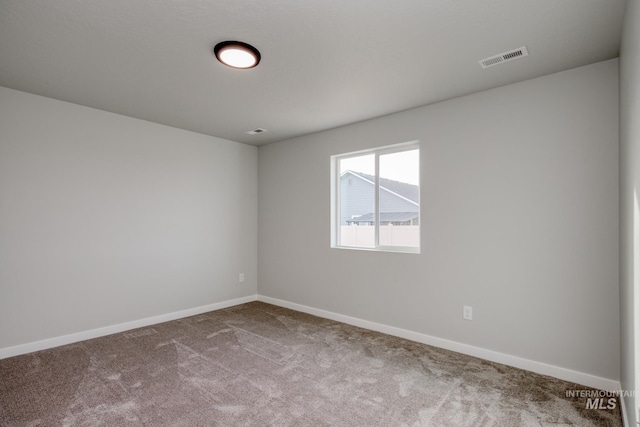 spare room with carpet flooring, baseboards, and visible vents