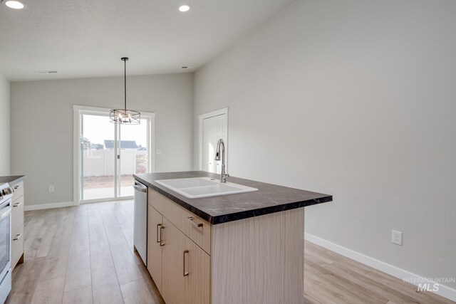 kitchen featuring dishwasher, a sink, light wood-style floors, vaulted ceiling, and dark countertops