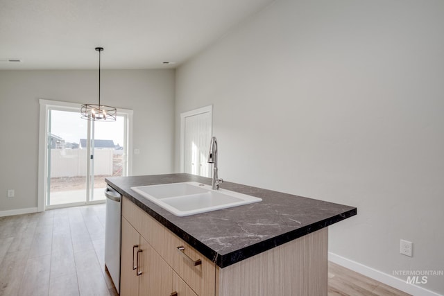 kitchen featuring a sink, vaulted ceiling, light brown cabinetry, stainless steel dishwasher, and light wood-style floors