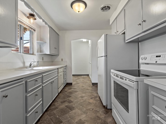 kitchen with white appliances, gray cabinetry, and sink