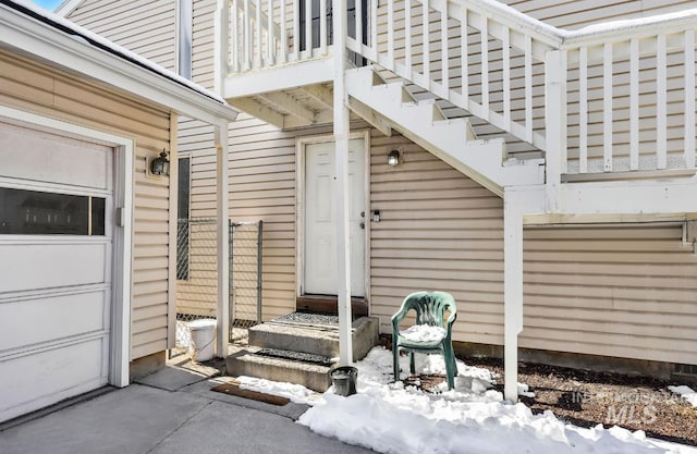 snow covered property entrance featuring a garage