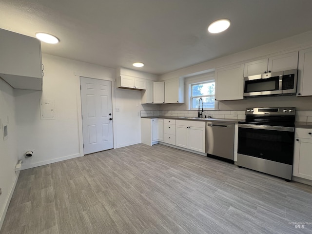 317 Baker Dr, Mountain Home, ID 83647 - kitchen with appliances with stainless steel finishes, light wood-style flooring, white cabinetry, dark countertops, and a sink