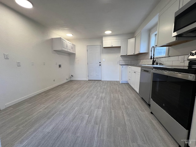 317 Baker Dr, Mountain Home, ID 83647 - kitchen with stainless steel appliances, a sink, light wood-style floors, baseboards, and white cabinetry