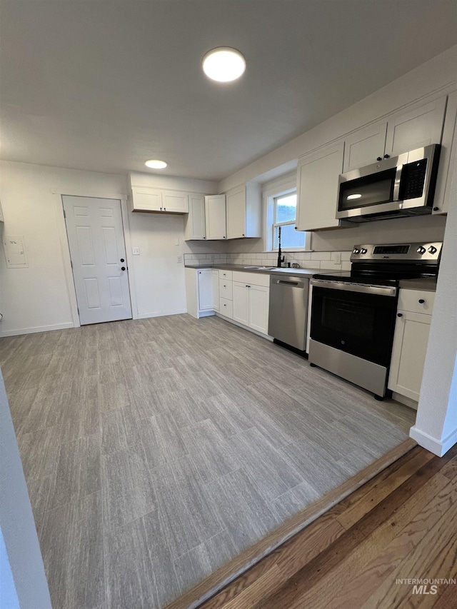 317 Baker Dr, Mountain Home, ID 83647 - kitchen with stainless steel appliances, light wood-type flooring, white cabinetry, and baseboards