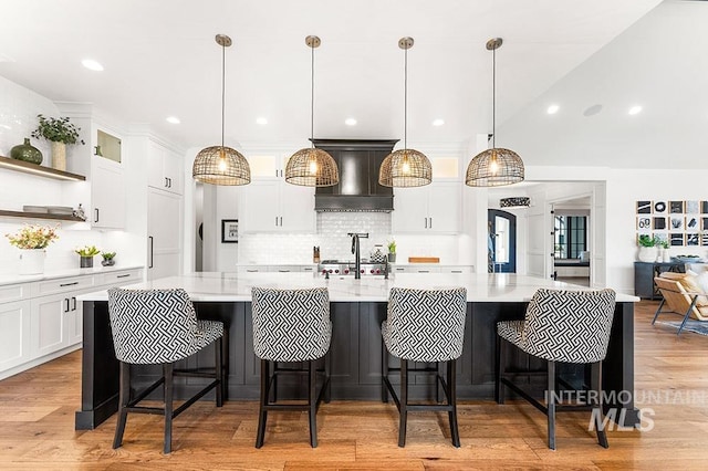 kitchen featuring open shelves, premium range hood, light wood-type flooring, and light countertops