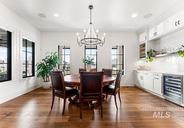 dining room featuring a wealth of natural light, beverage cooler, baseboards, and wood finished floors