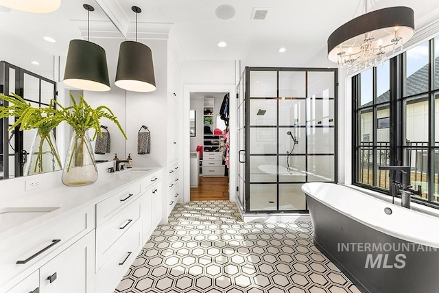 full bath featuring a sink, visible vents, a freestanding bath, a spacious closet, and a stall shower