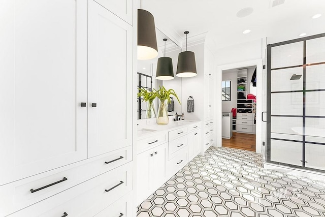 full bathroom featuring double vanity, a stall shower, a spacious closet, a sink, and recessed lighting