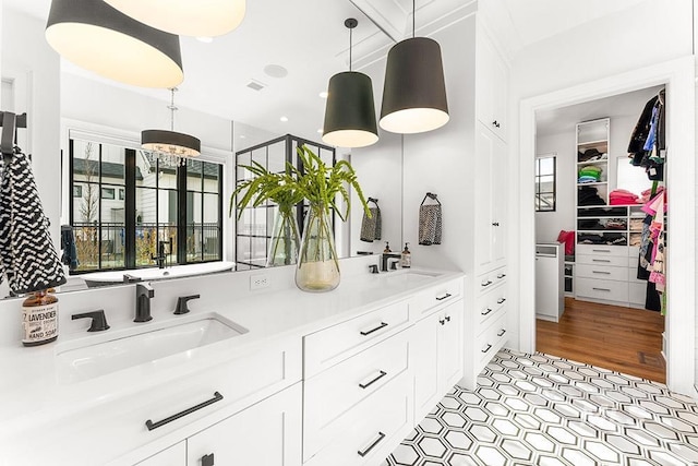 full bathroom featuring double vanity, a chandelier, a walk in closet, and a sink