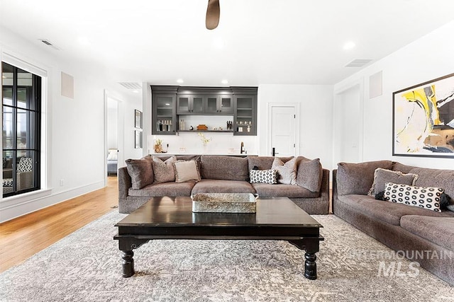 living area featuring light wood-type flooring, visible vents, indoor wet bar, and recessed lighting