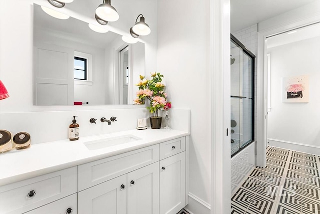 bathroom featuring combined bath / shower with glass door, vanity, and baseboards