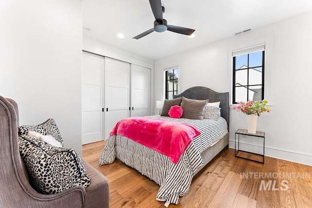 bedroom featuring baseboards, visible vents, ceiling fan, wood finished floors, and a closet