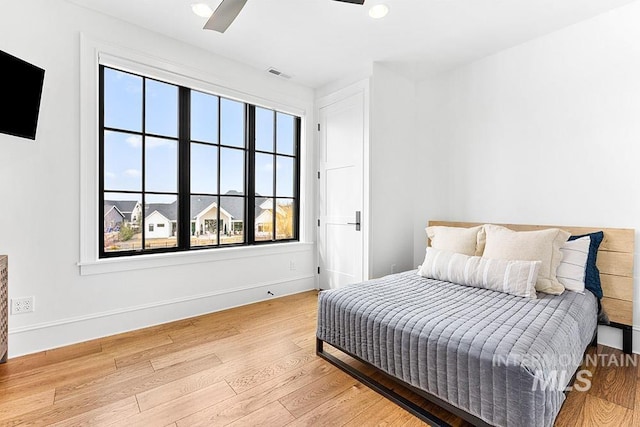 bedroom featuring ceiling fan, light wood-style flooring, visible vents, and baseboards