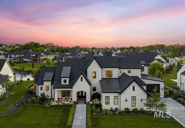 view of front of home featuring a standing seam roof, a residential view, metal roof, and a front yard