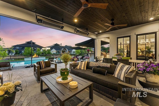 patio terrace at dusk featuring an outdoor hangout area, fence, and a fenced in pool