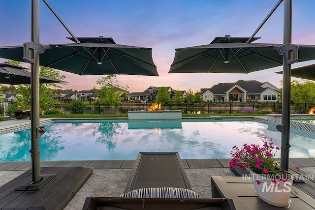 pool at dusk with fence and a fenced in pool