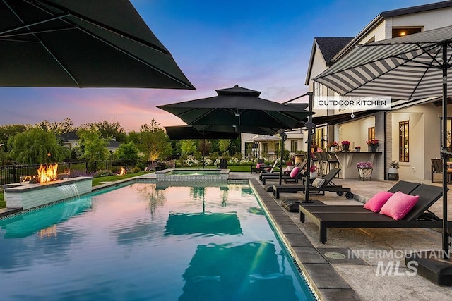 view of swimming pool with outdoor dry bar, a patio area, fence, and a pool with connected hot tub